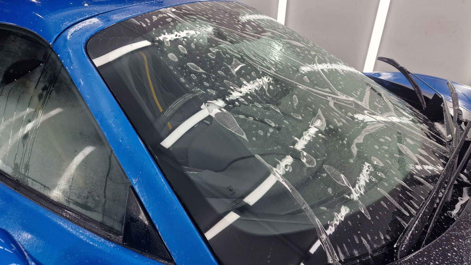 A blue Ferrari F8 getting windscreen film applied